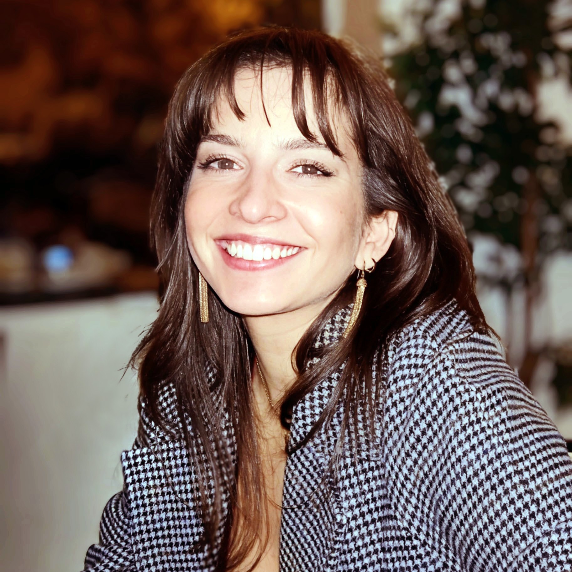 Portrait of a man with brown hair and glasses on a flat gray background.